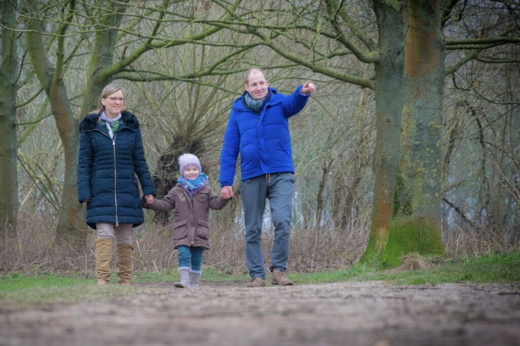 Familie mit Kind bei einem Spaziergang im Freien, natürlich fotografiert